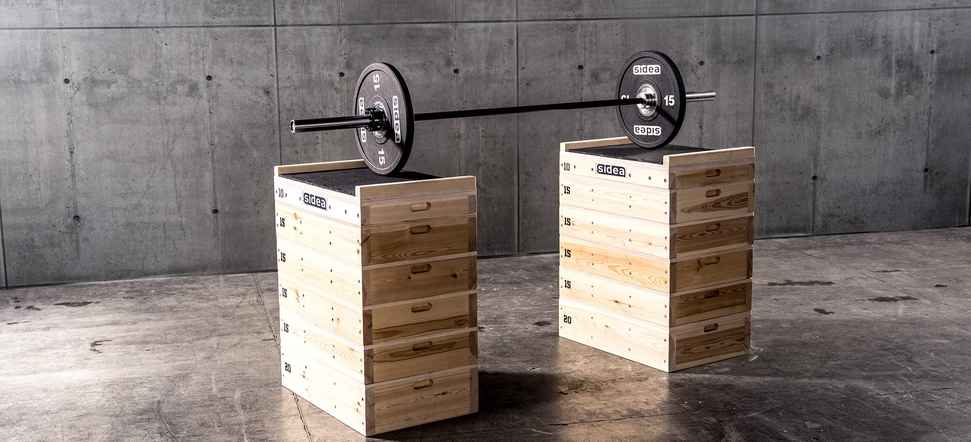 Sidea barbell accessories including Olympic collars, chalk, and barbell padding displayed on gym jerk blocks